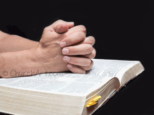 Open Bible photo with hands folded in prayer or meditation during bible study