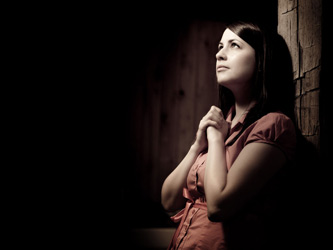 Young woman looking upward with clasped hands as background photo